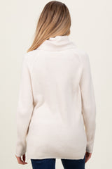 woman wearing a cream-colored maternity sweater with a cowl neck and ribbed texture, seen from the back
