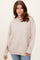 woman wearing a light beige oversized sweater with ribbed hem and relaxed fit paired with blue jeans