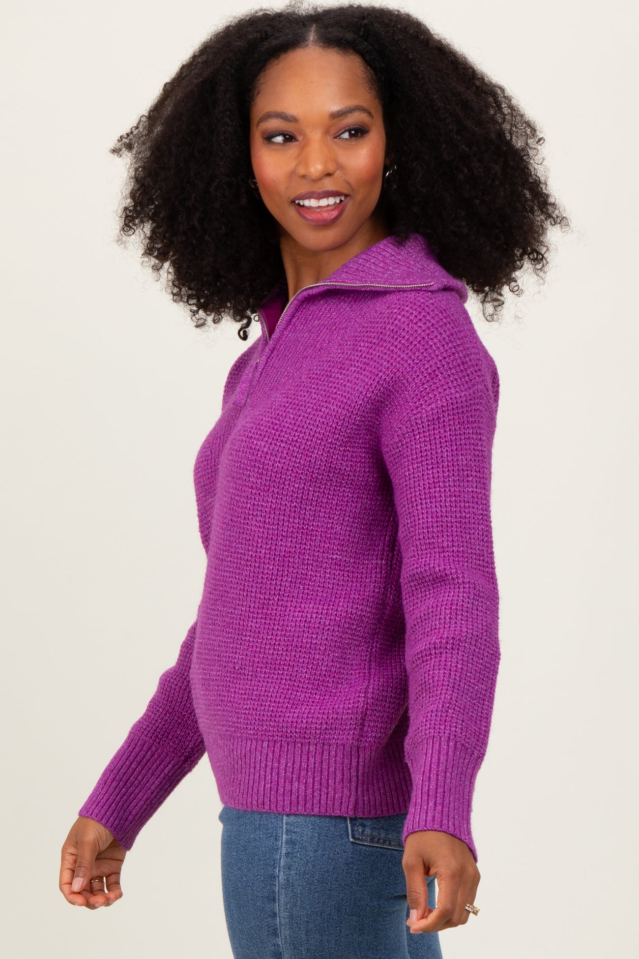 woman wearing a purple hooded knit sweater with a front zipper and ribbed cuffs, smiling at the camera
