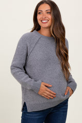 woman wearing a gray maternity sweater with side slits and holding her baby bump