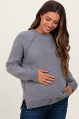 woman wearing a gray maternity sweater with ribbed hem and side slits, holding her baby bump