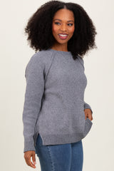 woman wearing a gray knit sweater with side slits and raglan sleeves, paired with blue jeans