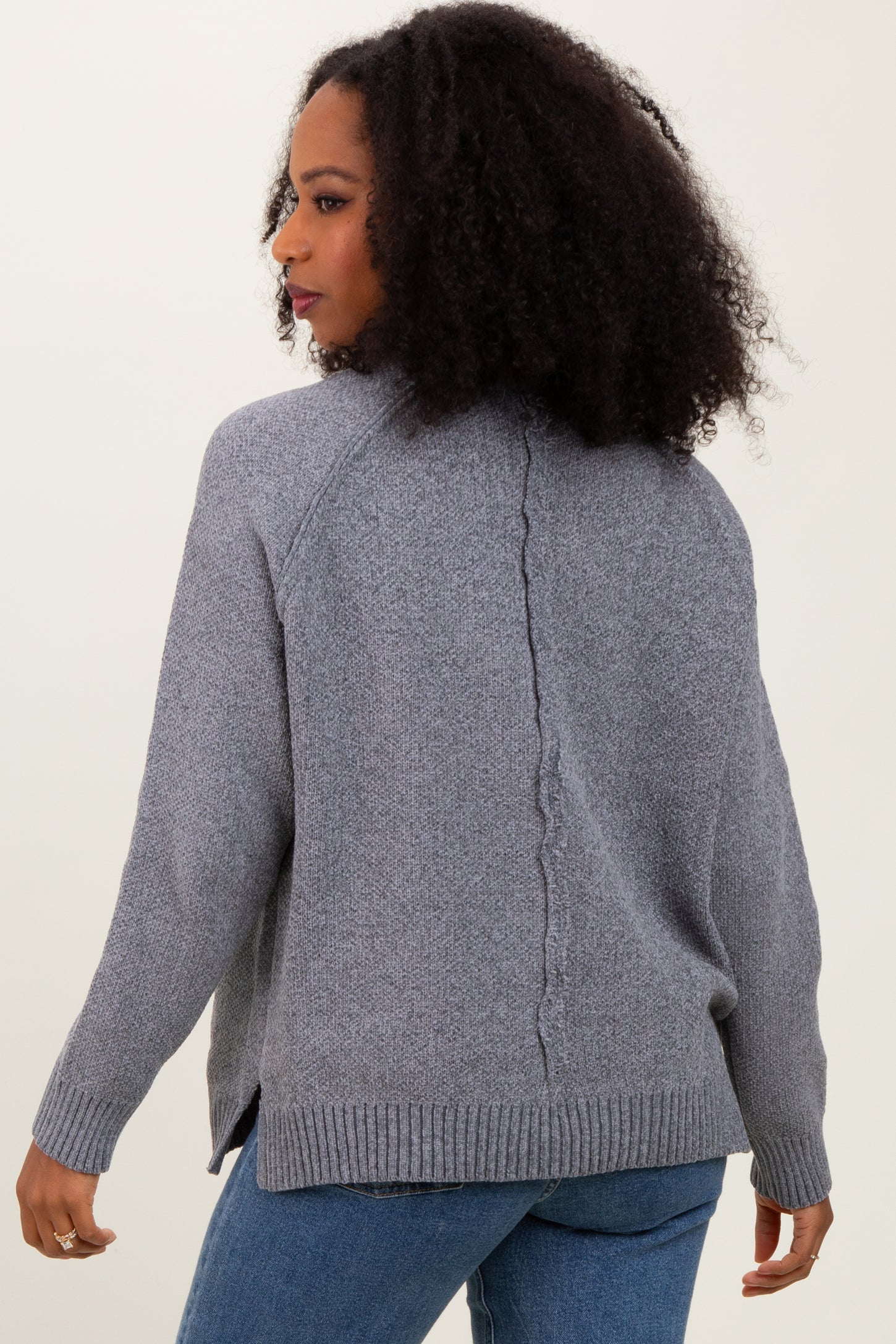 woman wearing a gray knit cardigan with a back seam detail and slouchy fit, paired with blue jeans