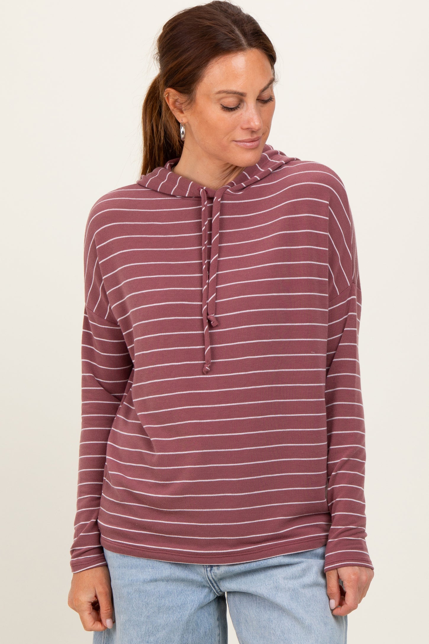 woman wearing a maroon striped pullover hoodie with a drawstring and relaxed fit