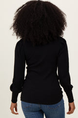 woman wearing a black ribbed long sleeve top with puffed shoulders and back view, paired with blue jeans