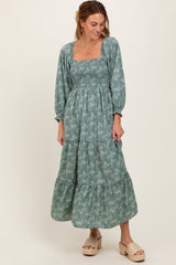 woman wearing a teal floral tiered maxi dress with a square neckline and long sleeves