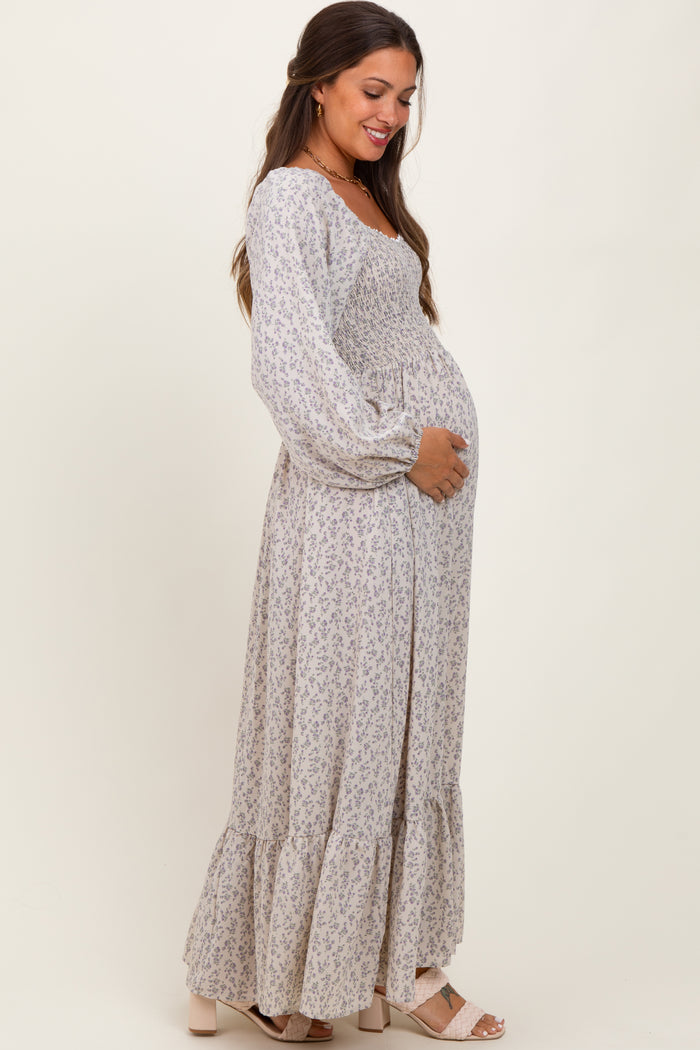 woman wearing a floral print long sleeve maternity dress and holding her baby bump
