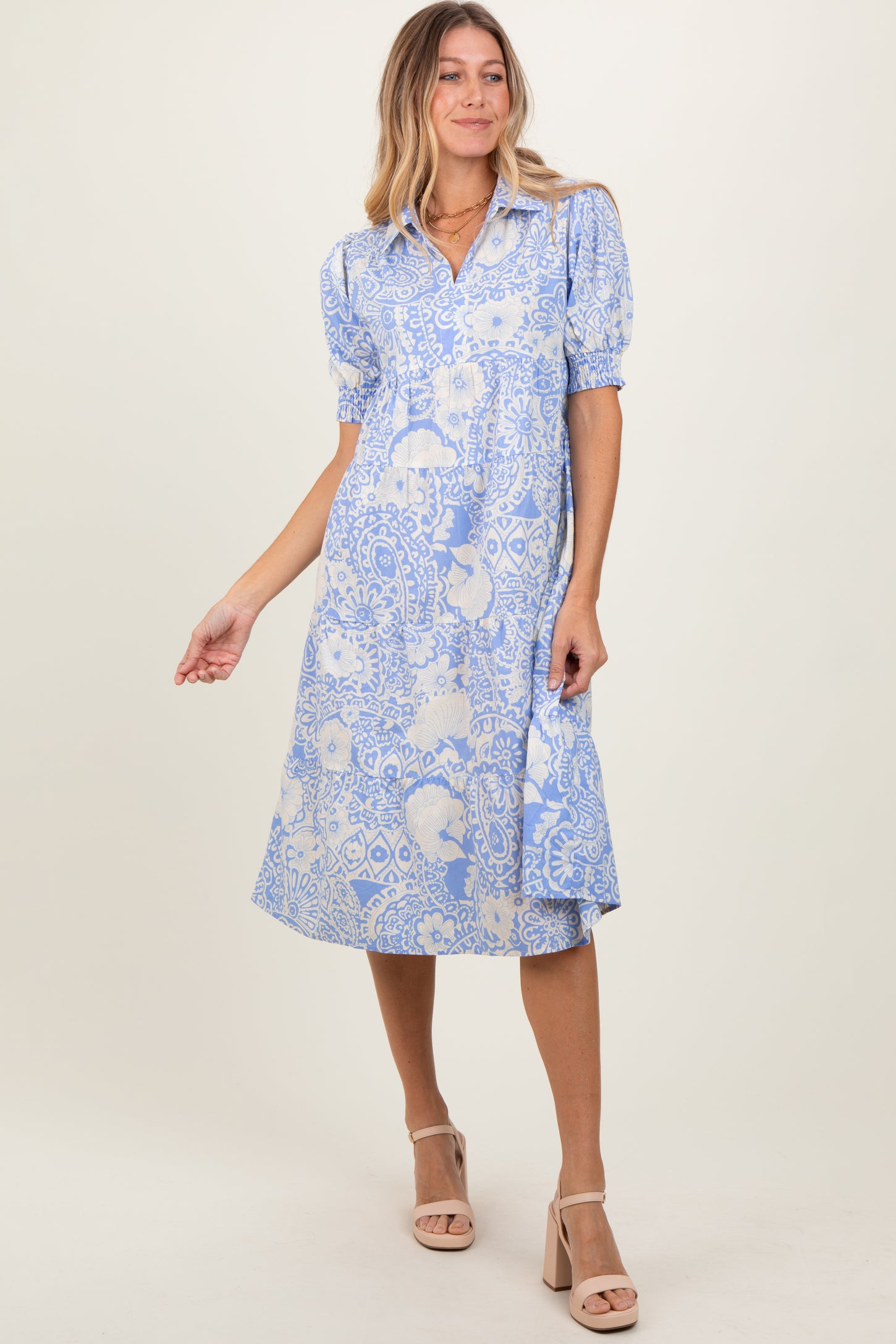 woman wearing a blue floral print midi dress with short puffed sleeves and a button-down front
