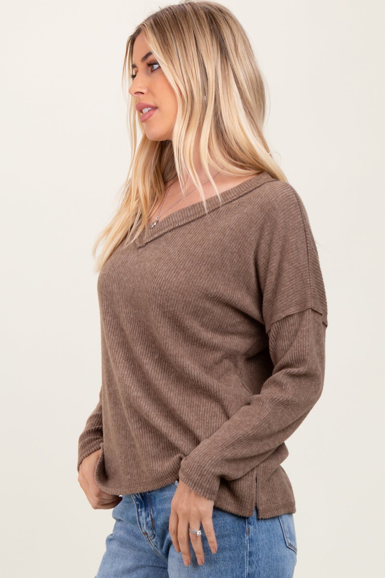 woman wearing a brown ribbed sweater with a v-neck and long sleeves, styled with light blue jeans