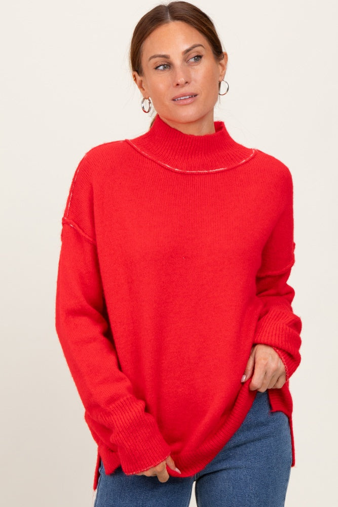 woman wearing a bright red oversized turtleneck sweater with side slits and a relaxed fit