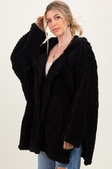 woman wearing a black oversized fuzzy hooded jacket with a relaxed fit and pockets