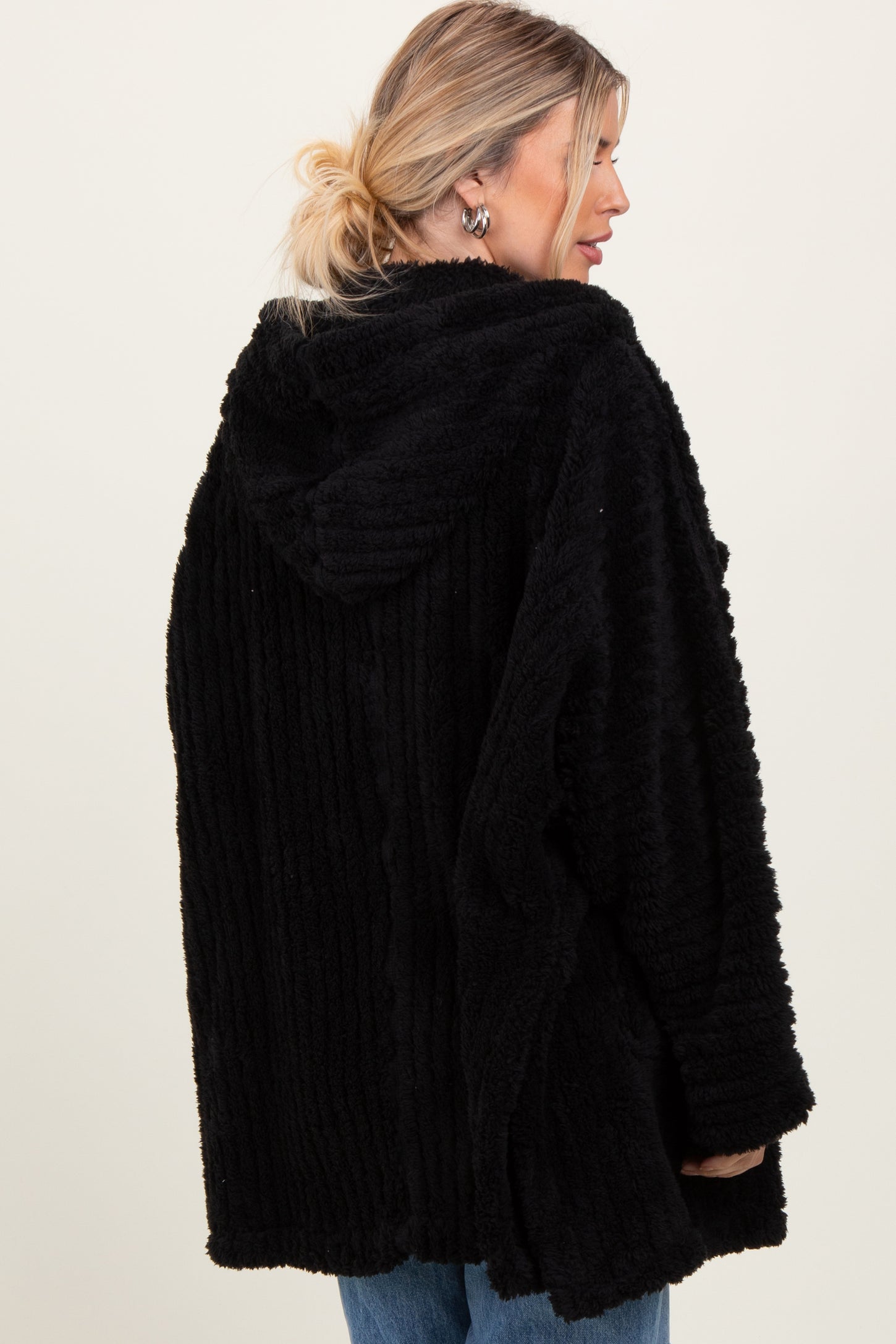 woman wearing a black fuzzy hooded cardigan with a ribbed texture, showcasing the back view and relaxed fit