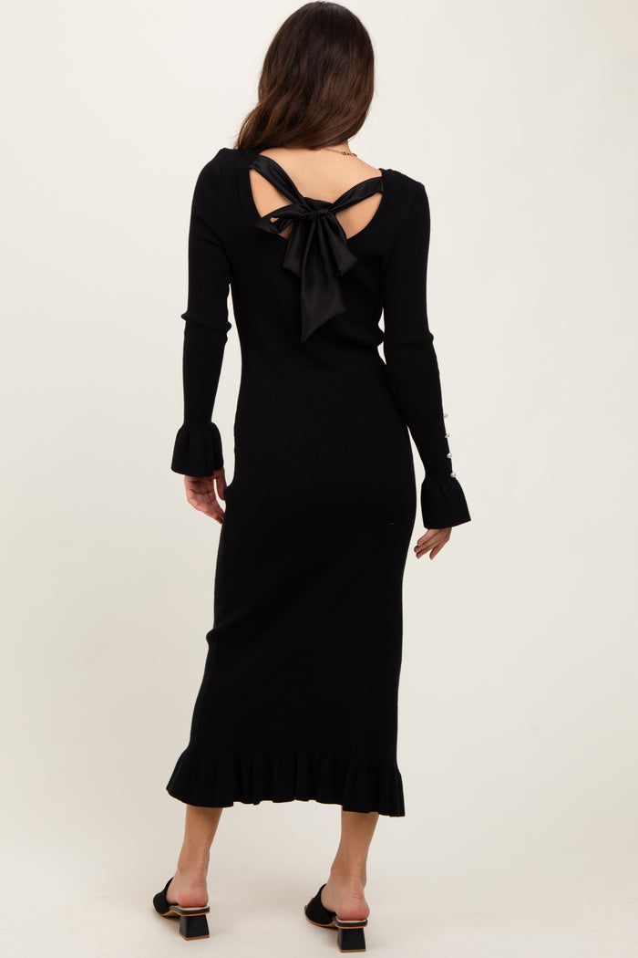 woman wearing a black ribbed midi dress with long sleeves and a bow detail at the back