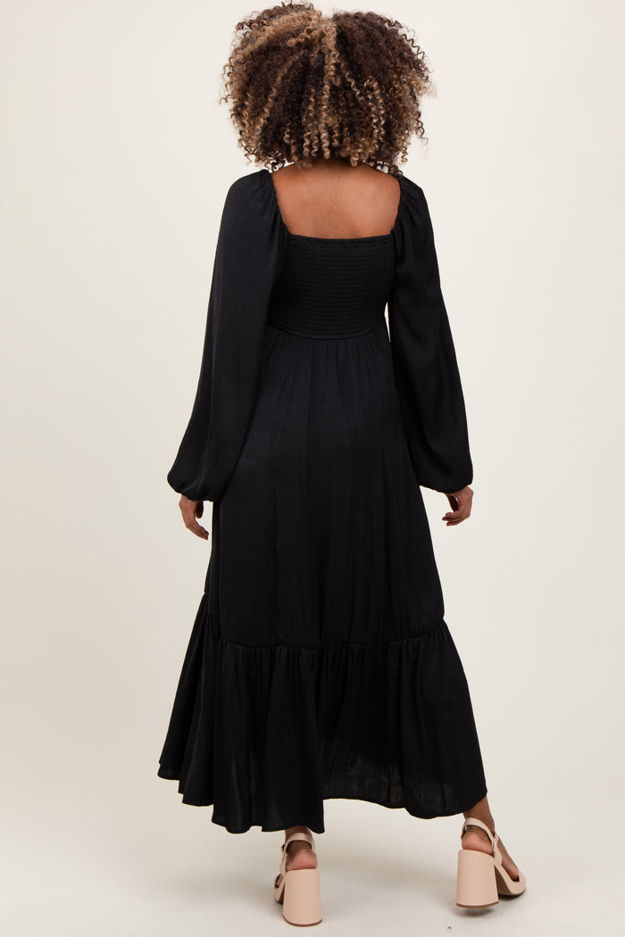 woman wearing a black long sleeve maternity dress with a smocked bodice and tiered skirt from the back