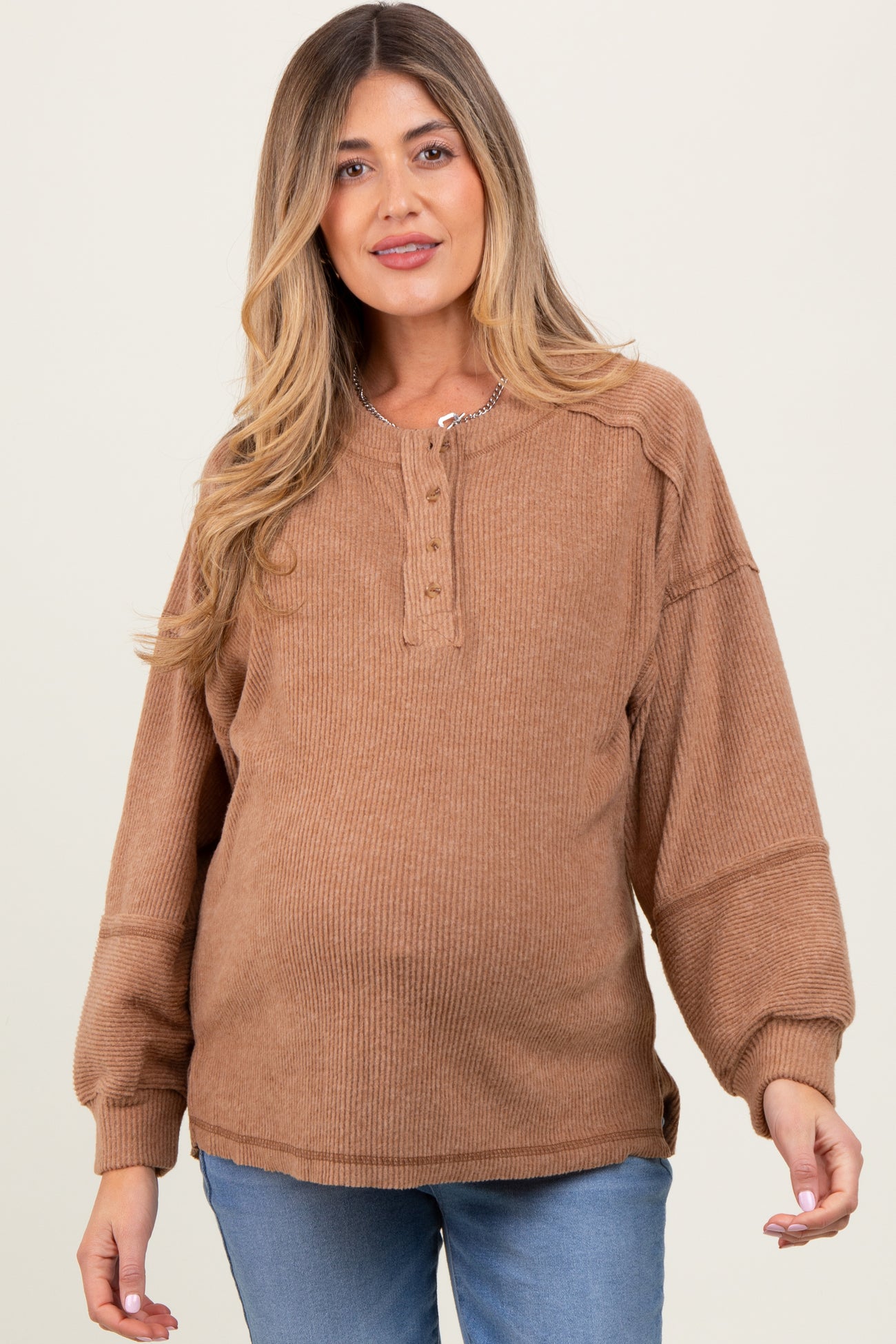 woman wearing a brown ribbed maternity sweater with a button-up neckline and a visible baby bump