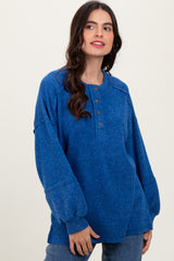 woman wearing a blue oversized henley sweater with buttons and long sleeves, styled with relaxed jeans