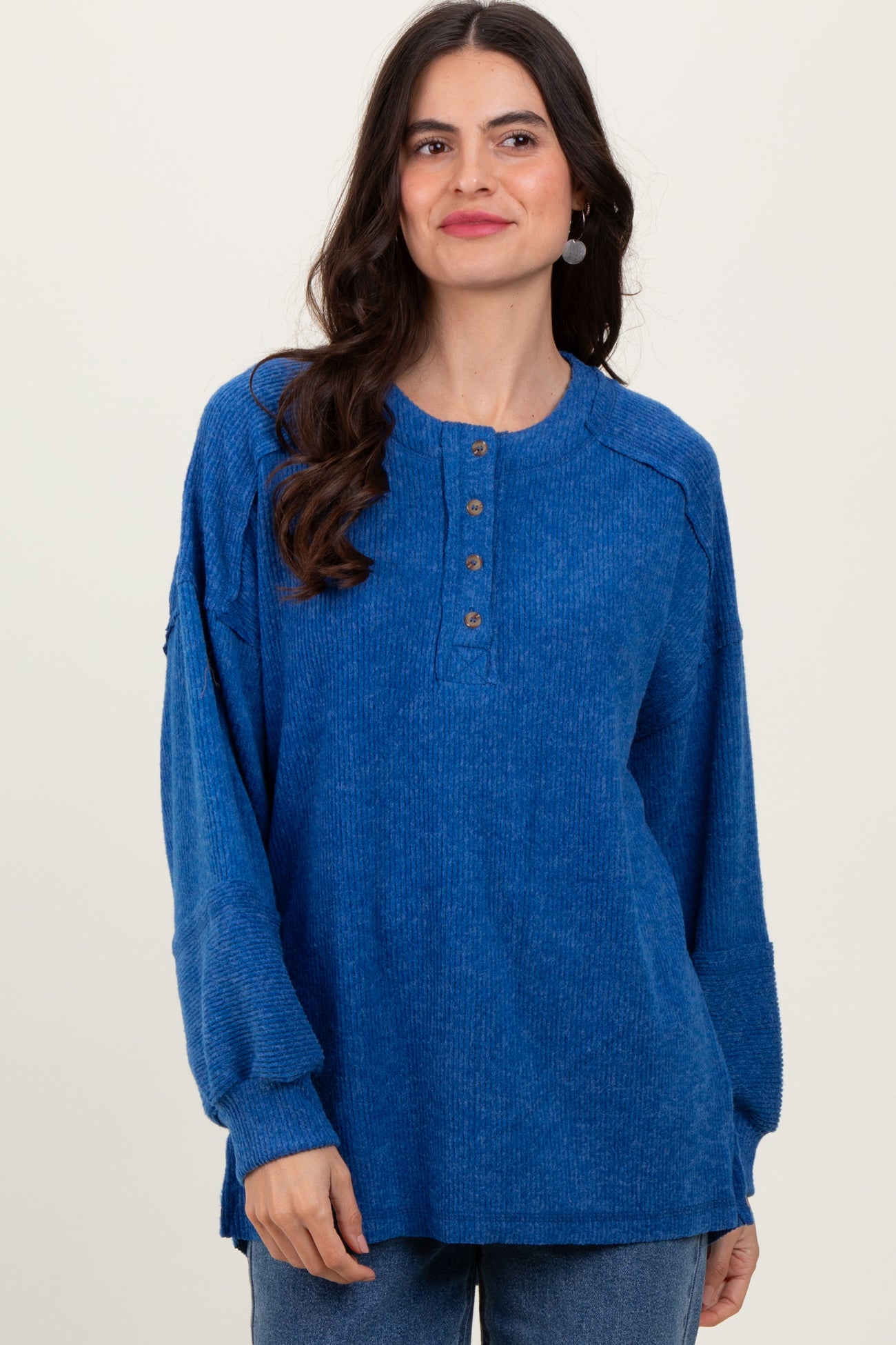 woman wearing a blue long sleeve henley top with button details and relaxed fit