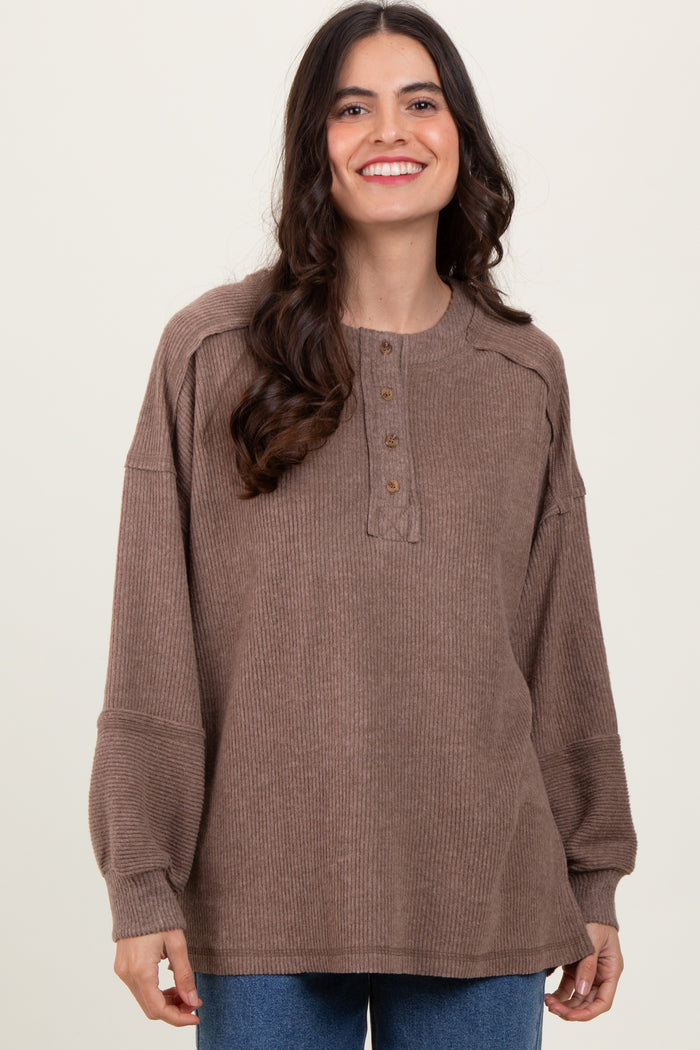 woman wearing a brown ribbed henley top with button detail and puffed sleeves
