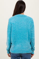 woman wearing a turquoise knit sweater with long sleeves and a ribbed hem, shown from the back