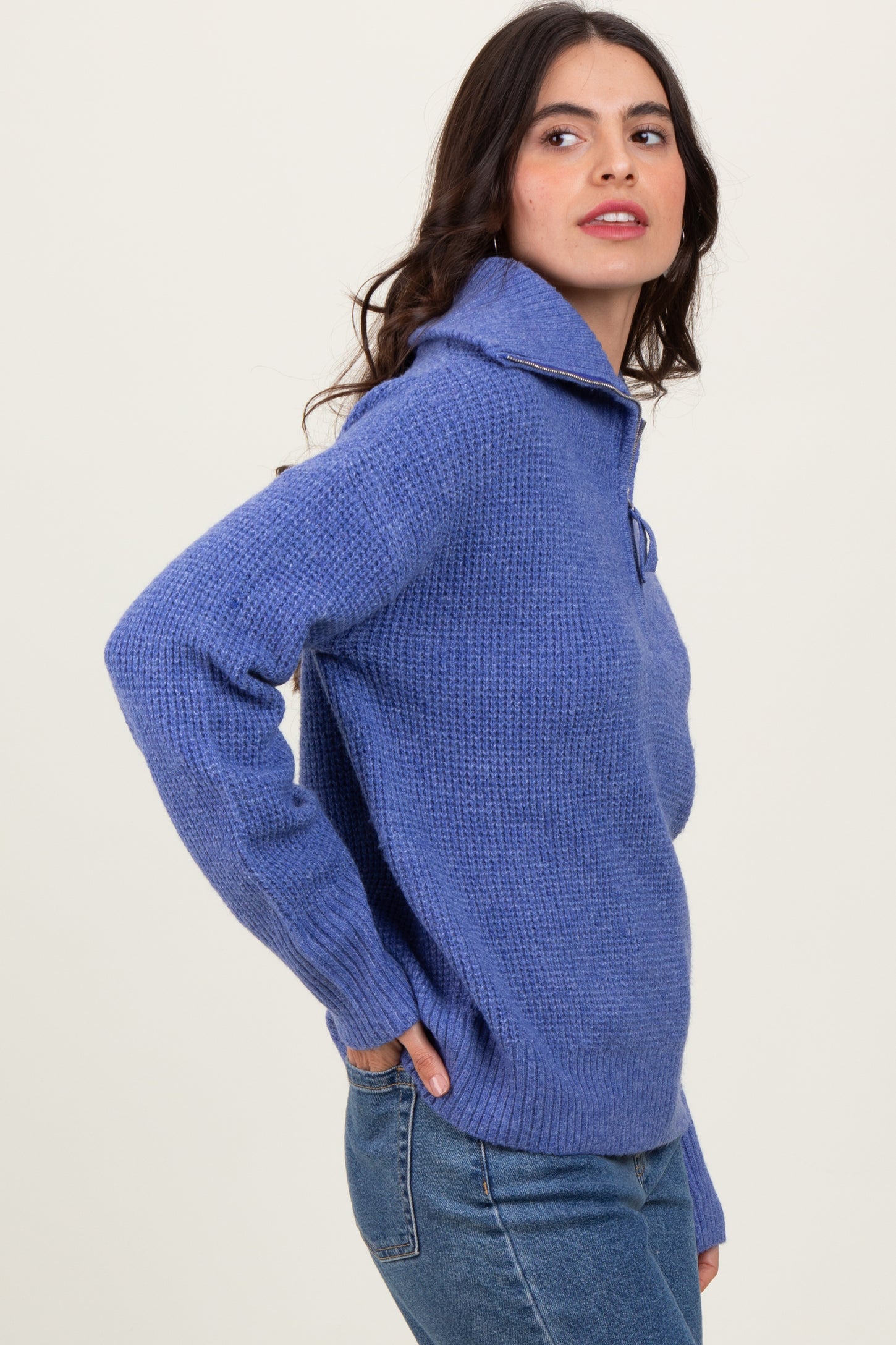 woman wearing a light purple knit pullover sweater with a folded collar and side pockets, paired with jeans