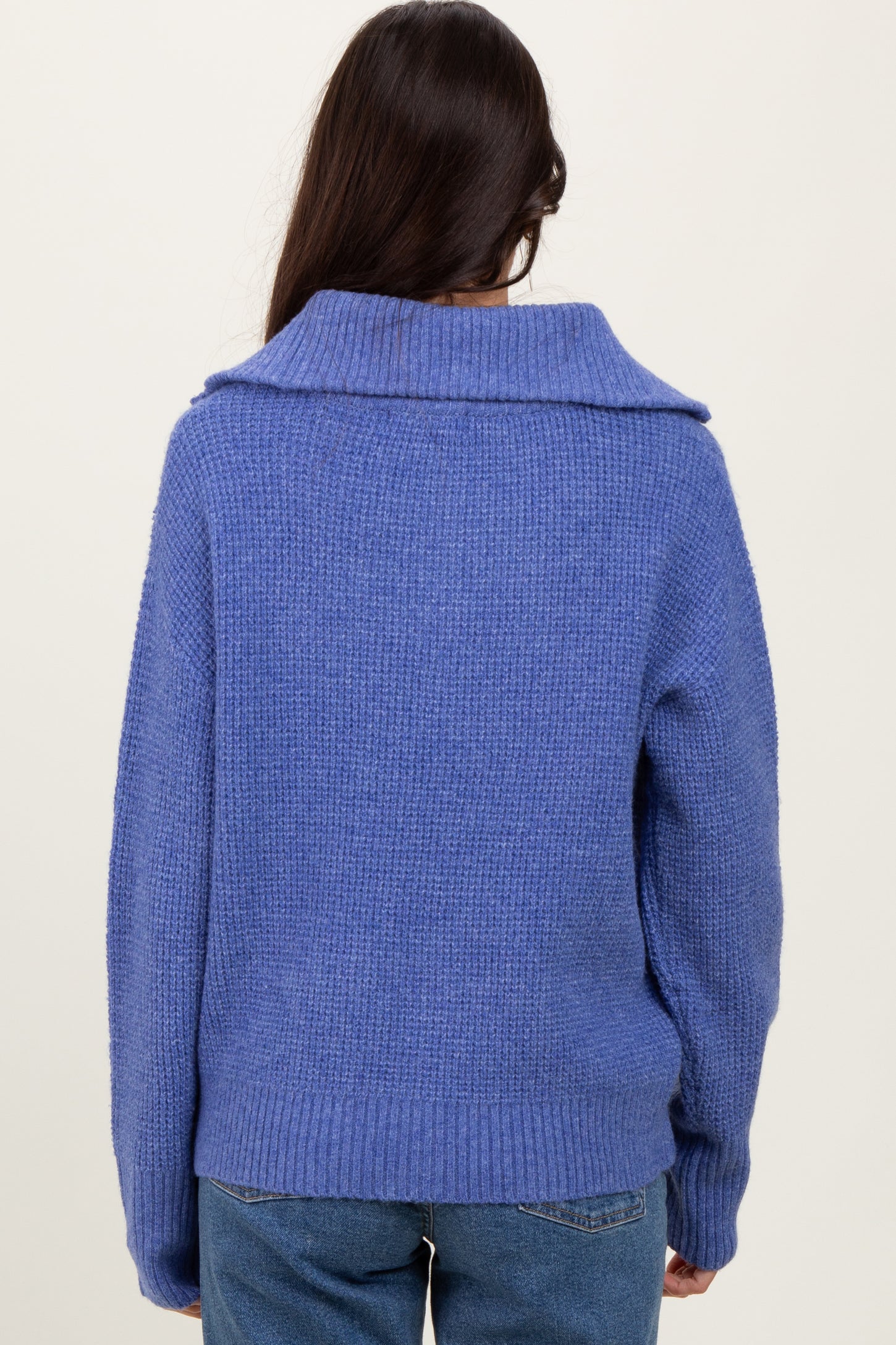 woman wearing a cozy blue sweater with a wide collar, seen from the back