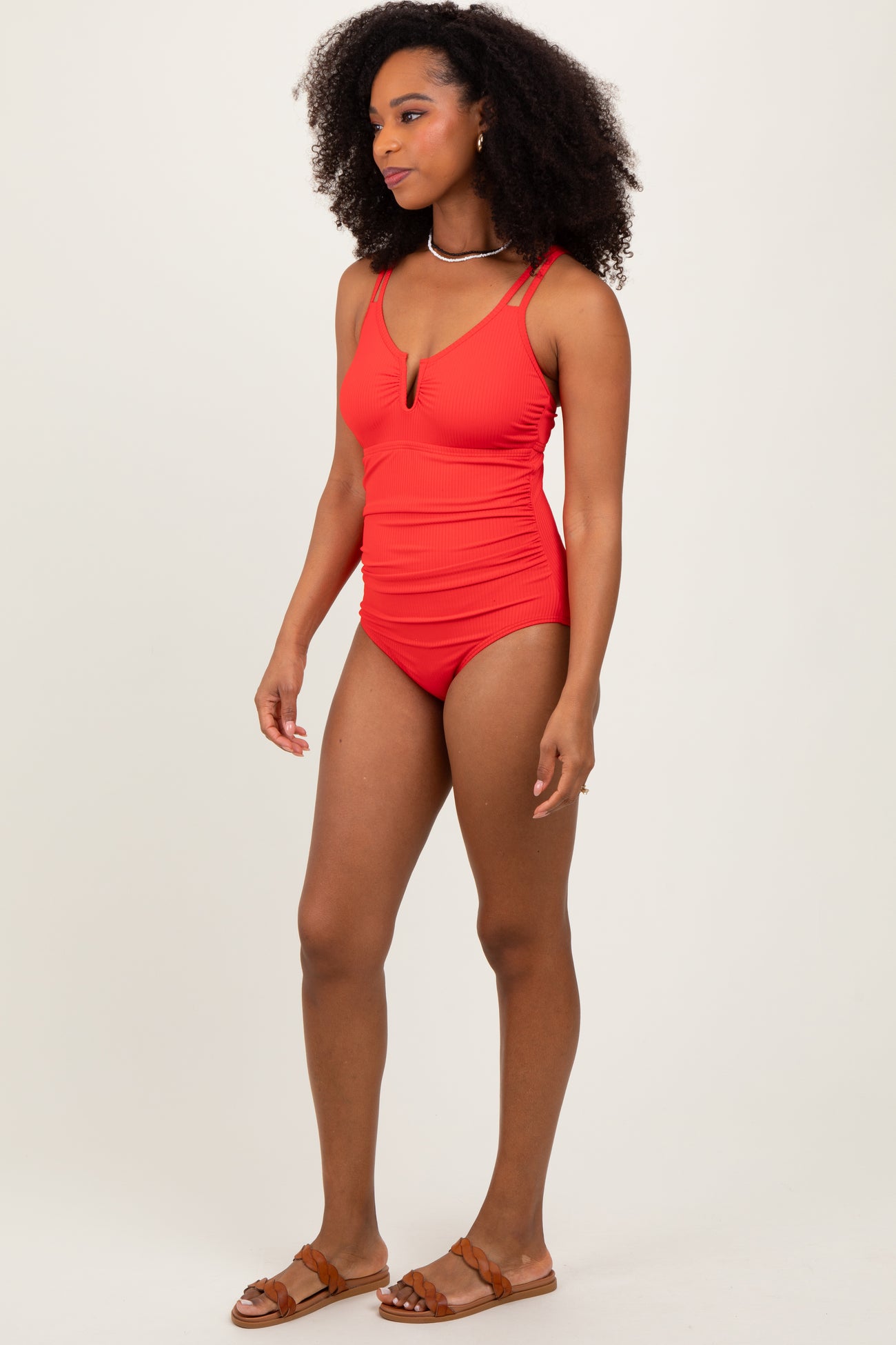woman wearing a red ribbed one-piece swimsuit with a deep V-neck and adjustable straps
