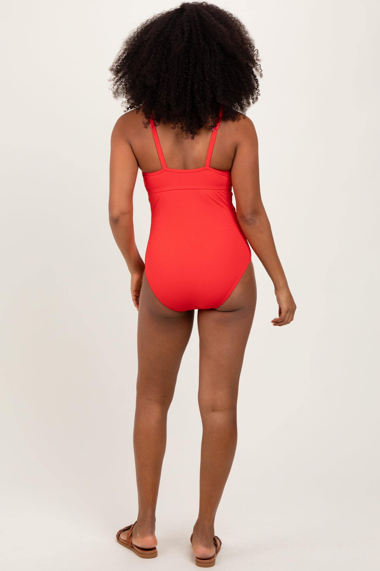 woman wearing a red ribbed one-piece swimsuit, viewed from the back