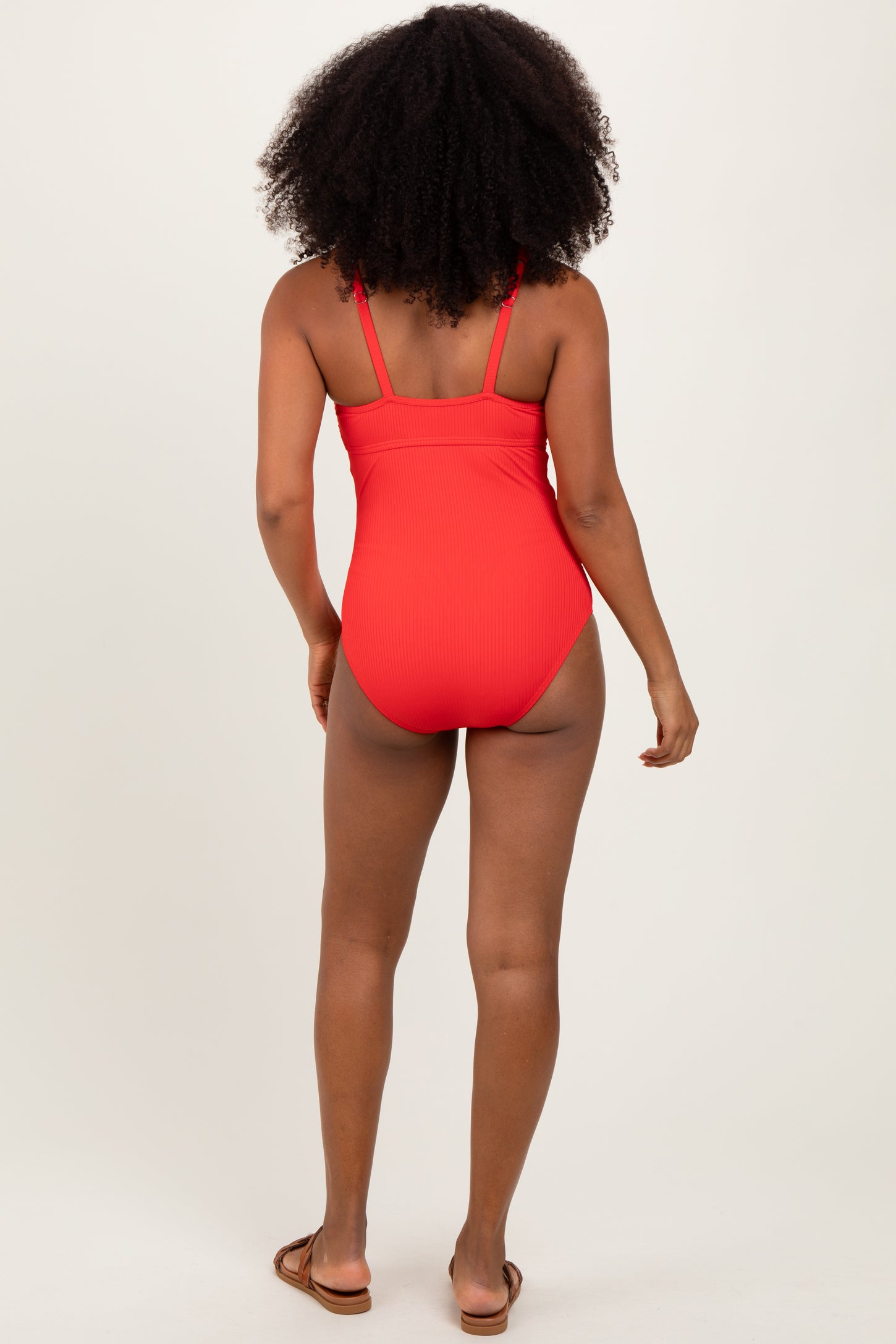 woman wearing a red ribbed one-piece swimsuit, viewed from the back