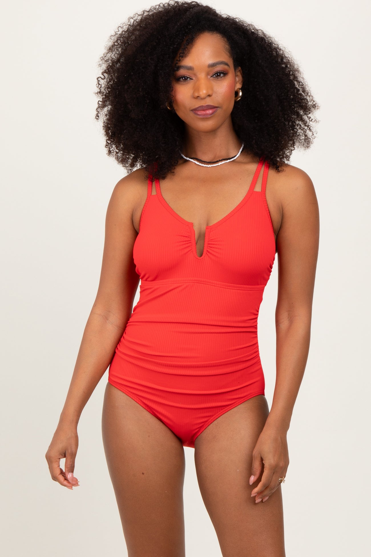 woman wearing a red ribbed one-piece swimsuit with a plunging neckline and double strap detail