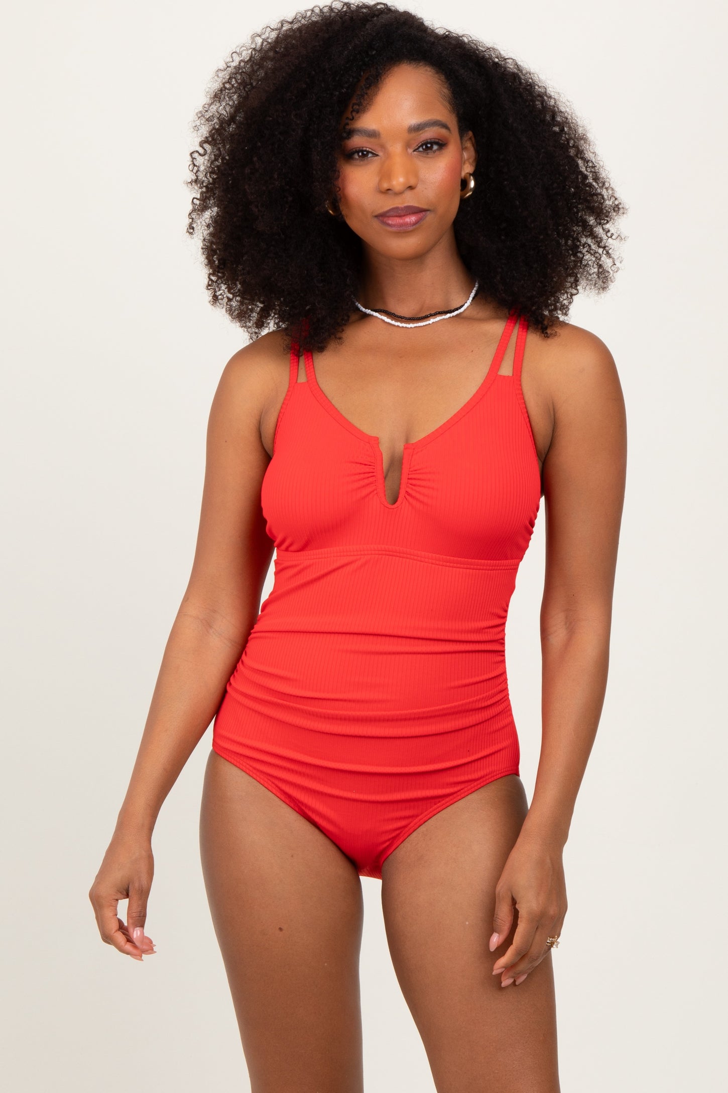 woman wearing a red ribbed one-piece swimsuit with a plunging neckline and double strap detail
