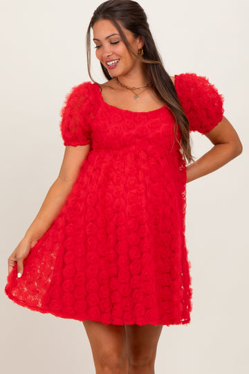 woman wearing a red maternity dress with puff sleeves and a textured rose pattern, smiling and showing her baby bump