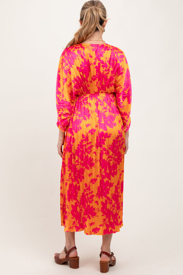 woman wearing a vibrant pink and yellow floral print maternity dress with long sleeves and a cinched waist, back view