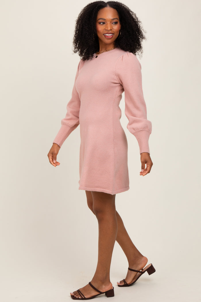 woman wearing a light pink long sleeve sweater dress with puffed sleeves and walking in a relaxed pose