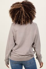 woman wearing a light gray maternity sweatshirt, seen from the back, paired with blue jeans
