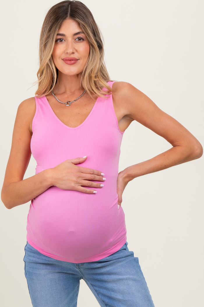 woman wearing a pink sleeveless maternity top and holding her baby bump