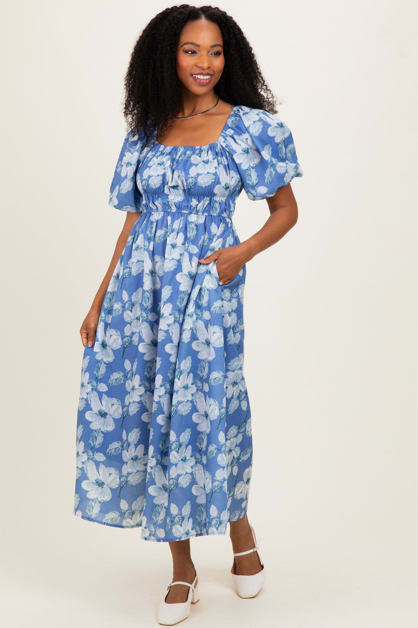 woman wearing a blue floral maxi dress with puff sleeves and pockets