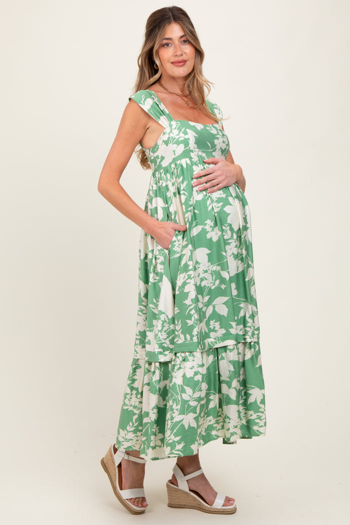 woman wearing a green floral maternity maxi dress with pockets and a visible baby bump