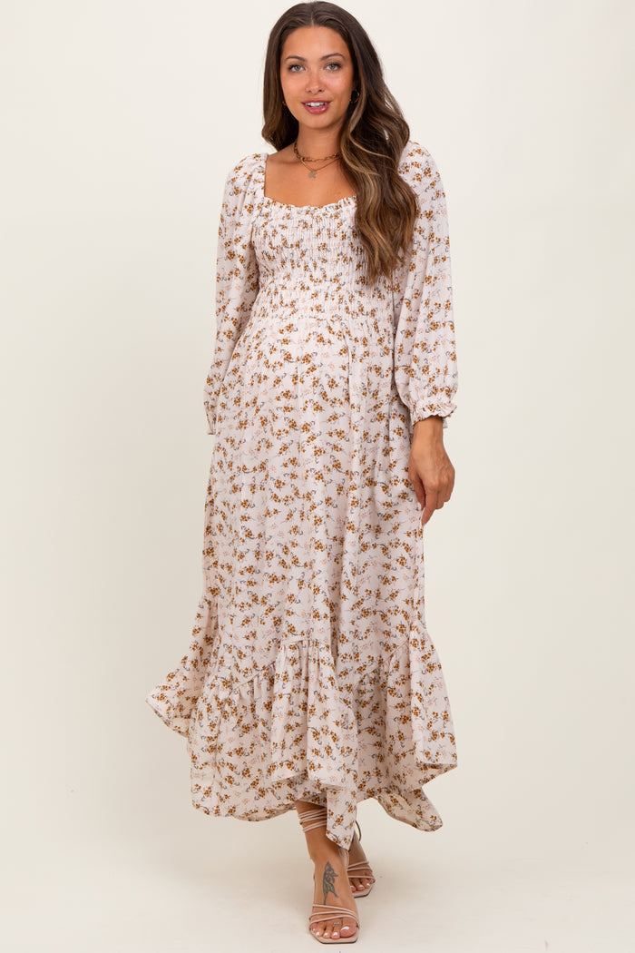 woman wearing a floral maternity maxi dress with puff sleeves and a ruffled hem