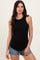 woman wearing a black ribbed tank top and denim shorts, standing against a neutral background