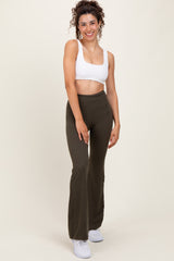 woman wearing a white cropped tank top and olive green flared leggings