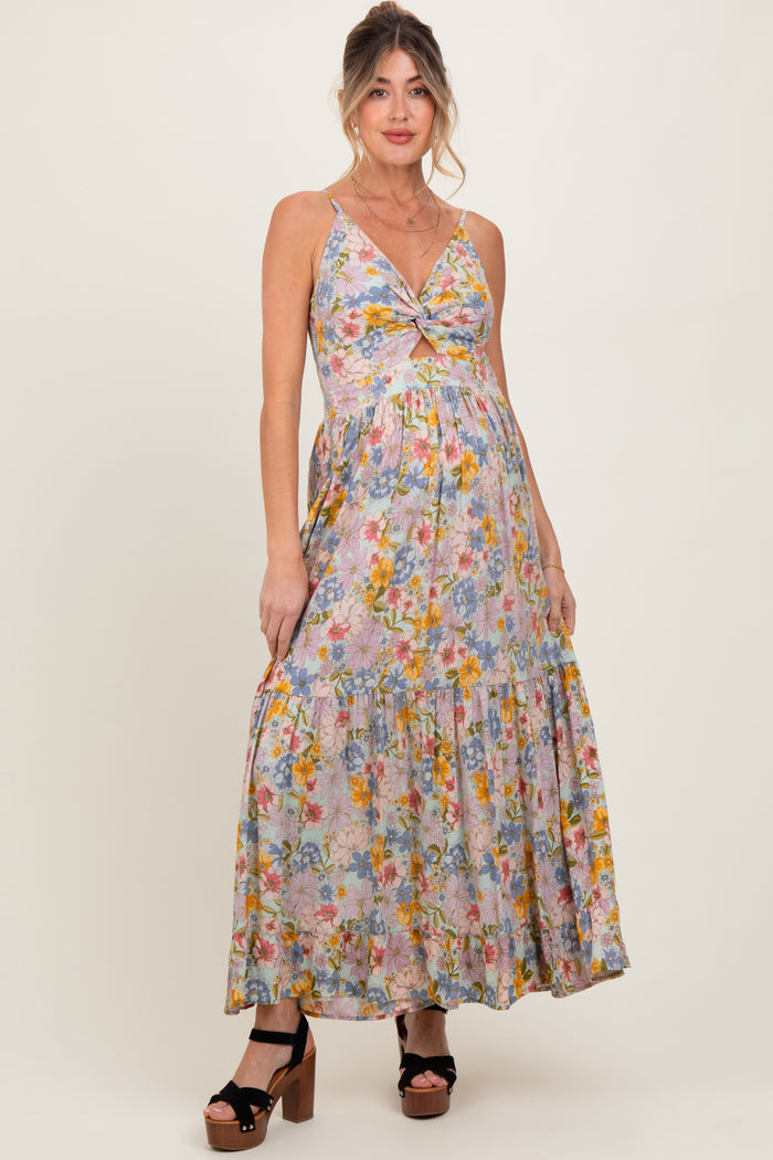 woman wearing a floral print maternity maxi dress with a twist front, showing a baby bump and wearing platform heels