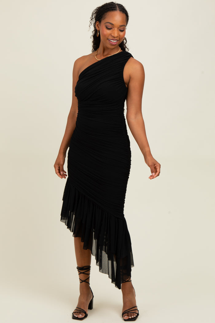 woman wearing a black one-shoulder ruched dress with a handkerchief hemline and strappy heels
