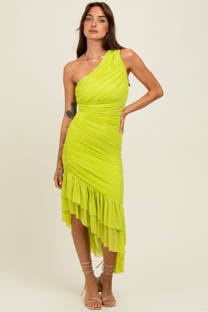 woman wearing a vibrant neon green one-shoulder dress with ruched detailing and a ruffled hem