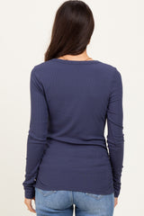 woman wearing a navy blue long sleeve ribbed top, viewed from the back with light blue jeans