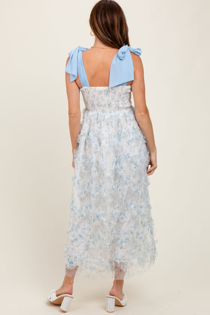 woman wearing a light blue floral midi dress with a smocked bodice and tie shoulder straps, seen from the back