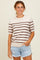 woman wearing a cream striped short sleeve sweater with brown stripes and denim shorts
