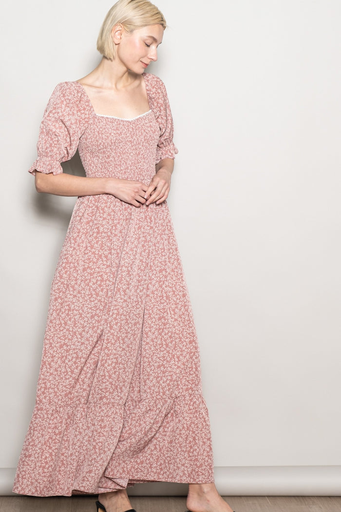 woman wearing a pink floral maxi dress with puff sleeves and a square neckline, standing against a neutral background