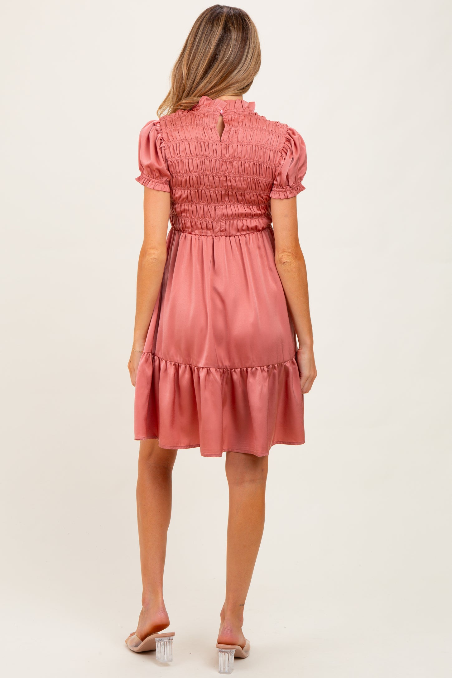 woman wearing a rose pink maternity dress with smocked bodice and ruffled hem, viewed from the back