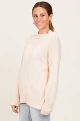 woman wearing a light beige oversized sweater with ribbed hem and long sleeves