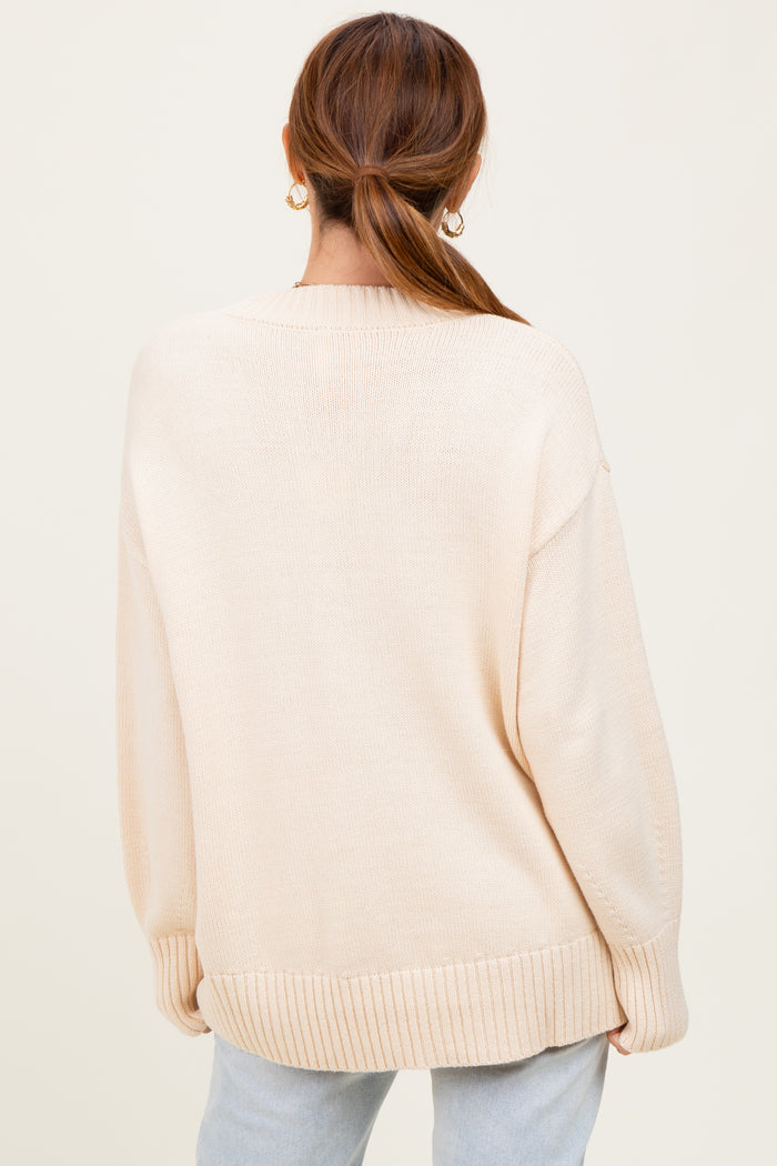 woman wearing a beige oversized sweater with ribbed hem and cuffs, seen from the back